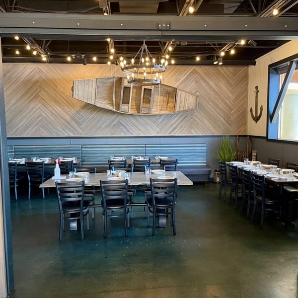 The Lake House Kitchen & Tavern dining room with tables, chairs, and a decorative boat on the wall.
